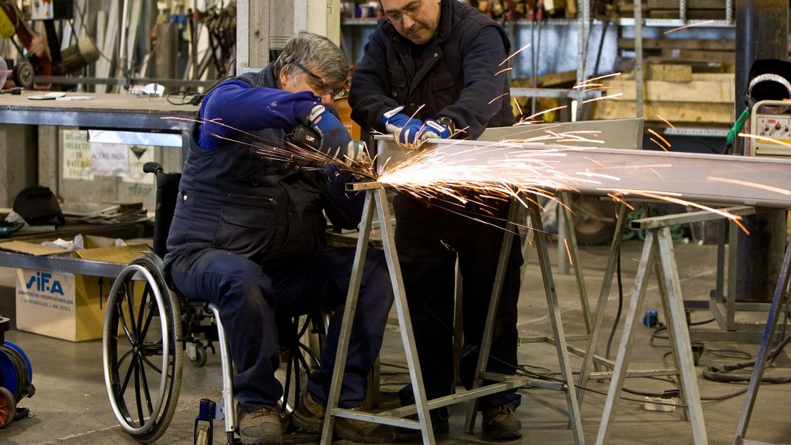 persona-en-silla-de-ruedas-acompanada-de-otra-esta-utilizando-una-moladora-sobre-hierro-67fe43bd31612917313494.jpg